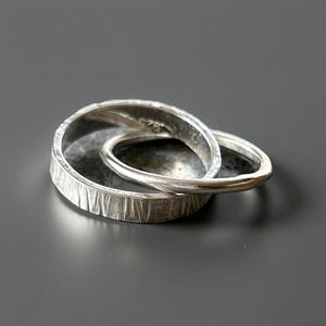 May include: Two interlocking silver rings, one with a textured finish and the other with a smooth finish.