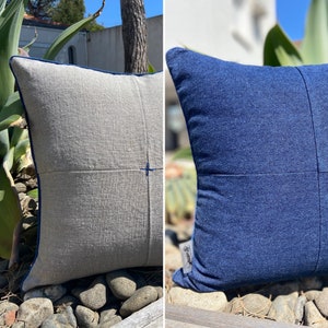Peut inclure: Deux coussins carrés avec une bordure bleue. Le coussin de gauche est en lin gris clair. Le coussin de droite est en denim bleu foncé.