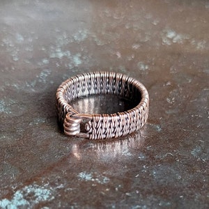 Könnte beinhalten: Ein Ring aus geflochtenem Silberdraht mit einem Verschluss.