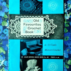 May include: A vintage crochet book titled "Old Favourites Crochet Book" in blue and white. The cover displays crochet doilies and a living room scene. The book is set against a floral background. The price is 1s. 9d.