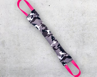 Puede incluir: Un juguete para perros de camuflaje con asas rosas. El juguete está hecho de tela y está diseñado para ser duradero para masticar.