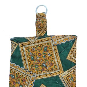 May include: A small, quilted fabric pouch with a loop handle. The pouch is made of green and yellow fabric with a floral pattern.