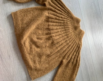 May include: A brown knitted sweater with a high neck and long sleeves. The sweater has a textured, ribbed pattern.