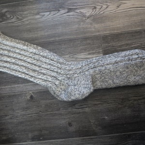 May include: A pair of gray and white knitted socks with a ribbed texture.