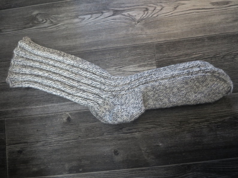 May include: A pair of gray and white knitted socks with a ribbed texture.