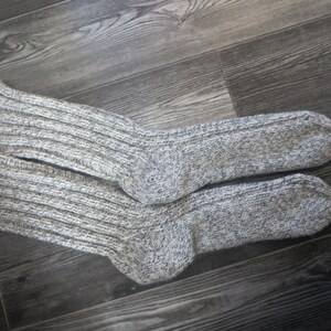 May include: A pair of gray knitted socks with a ribbed texture. The socks are made of a soft, warm material and are perfect for cold weather.
