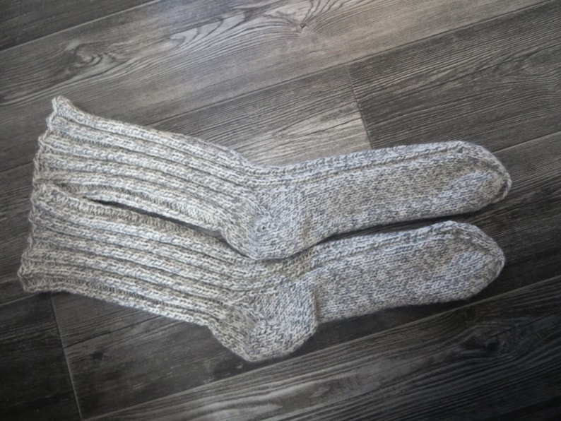 May include: A pair of gray knitted socks with a ribbed texture. The socks are made of a soft, warm material and are perfect for cold weather.