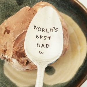 May include: A silver spoon with the words "World's Best Dad" engraved on it. The spoon is resting on a bowl of chocolate ice cream.
