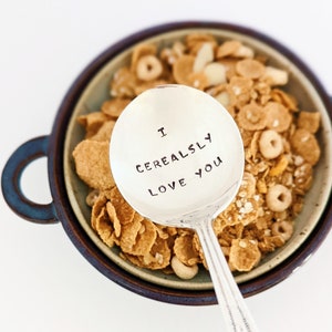 K&ouml;nnte beinhalten: Ein silberner L&ouml;ffel mit der Gravur "I Cerealsly Love You" auf der Schale. Der L&ouml;ffel liegt in einer Sch&uuml;ssel mit M&uuml;sli.