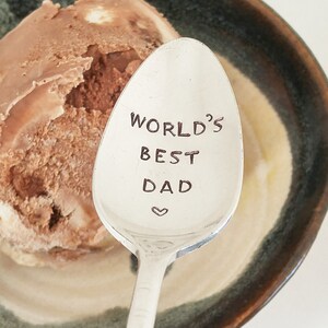 May include: A silver spoon with the words "World's Best Dad" engraved on it. A heart symbol is below the text.