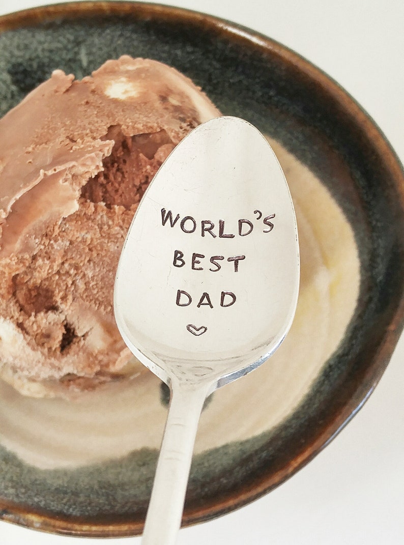 May include: A silver spoon with the words "World's Best Dad" engraved on it. A heart symbol is below the text.