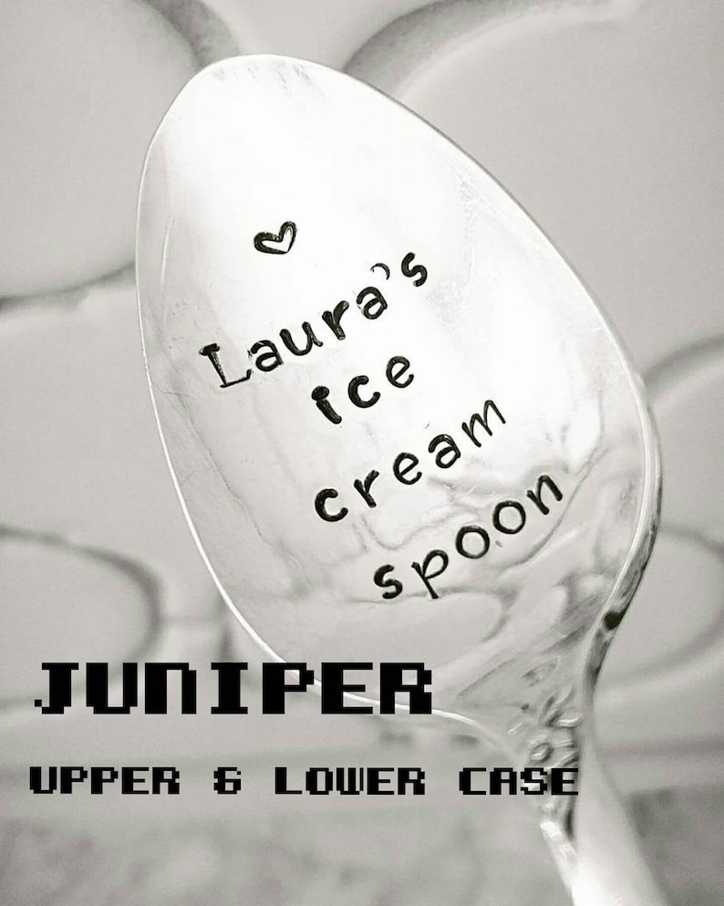 May include: A silver ice cream spoon with the text "Laura's ice cream spoon" and a small heart. The word "JUNIPER" is printed in a pixelated font, with "UPPER & LOWER CASE" below it.