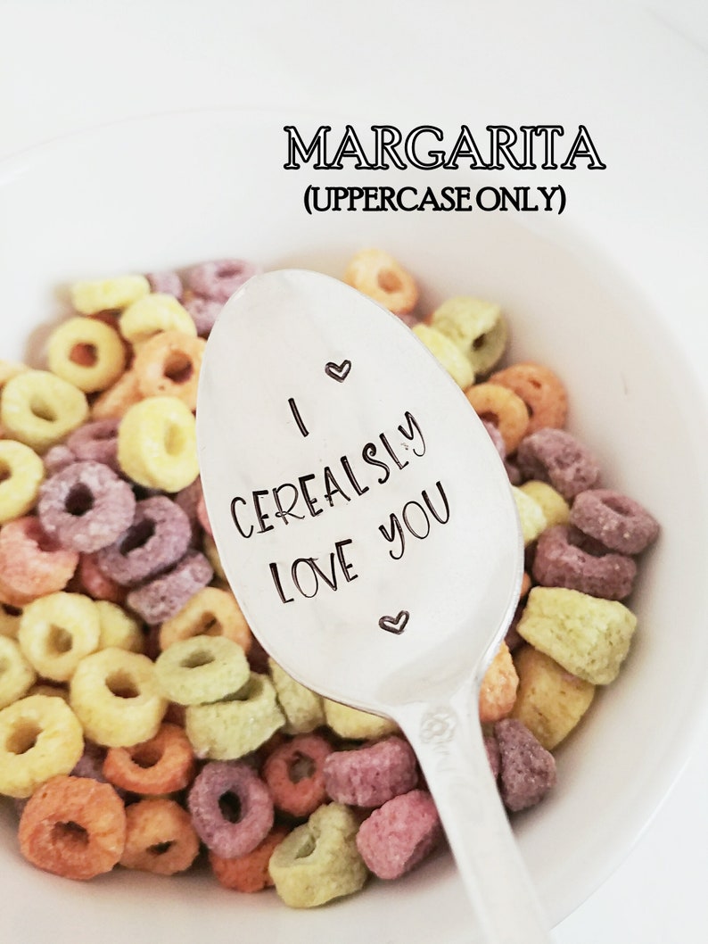 May include: A white ceramic bowl filled with colorful cereal, with a silver spoon that reads "I Cerealsly Love You." The word "Margarita" is above the bowl in uppercase letters.
