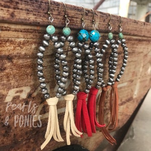 May include: Four pairs of silver bead earrings with turquoise stones and leather tassels. The tassels are in cream, red, and brown.