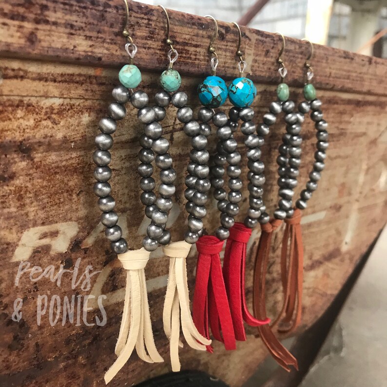 May include: Four pairs of silver bead earrings with turquoise stones and leather tassels. The tassels are in cream, red, and brown.