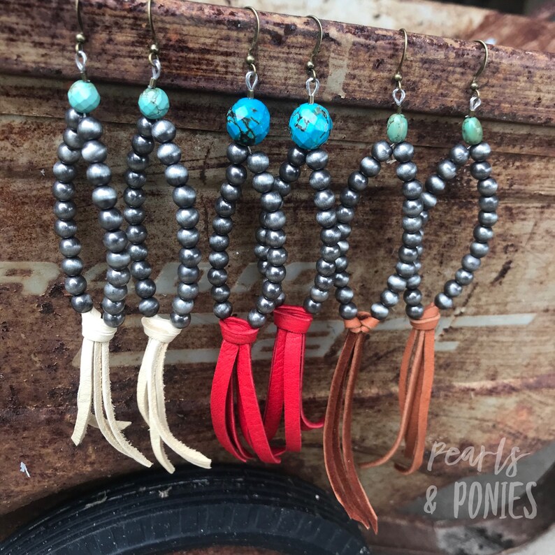 May include: Four pairs of silver bead earrings with turquoise accents and leather tassels. The tassels are white, red, brown, and orange.