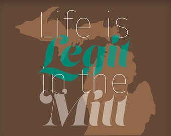 May include: A framed print with a brown background and a teal green frame. The print features a stylized outline of the state of Michigan with the text "Life is legit in the Mit" in white and teal green lettering.