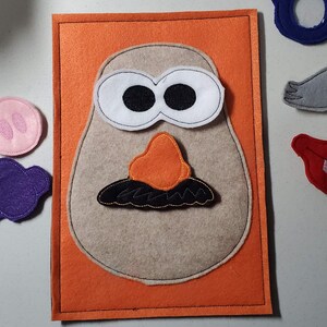 May include: A felt craft set for making a potato head character. The set includes a brown felt potato head base, two white eyes, a red nose, a black mustache, a gray mustache, a pink nose, a purple nose, a red mouth, and blue glasses.