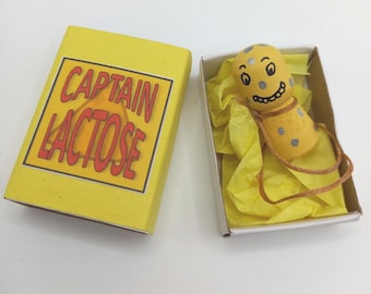 Captain Lactose in a Matchbox - small, cheesy peg doll.