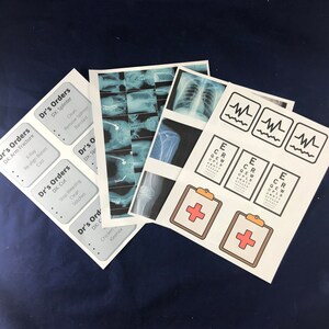 May include: A set of printable doctor's orders and medical themed images. The images include x-rays, an eye chart, a heart rate monitor, and a plus sign on a clipboard. The text on the printable doctor's orders includes "DX: Arm Fracture", "DX: Splinter", "DX: Cut", and "DX: Chicken Pox".
