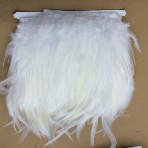 以下が含まれることがあります： 白い羽根のトリム、クラフトや装飾用の柔らかくふわふわの羽根のトリムです。