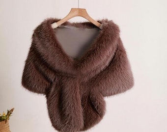 Peut inclure: Un châle en fausse fourrure marron avec une texture douce et moelleuse. Le châle est drapé sur un cintre en bois et présente un design simple et élégant.