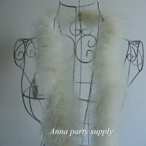 Op de afbeelding: Een witte verenboa gedrapeerd over een wit metalen mannequin. De boa is lang en pluche, en het mannequin staat op een witte achtergrond. De tekst "Anna party supply" is zichtbaar onderaan de afbeelding.