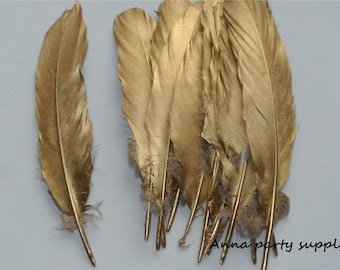 May include: A bunch of gold feathers, some are laying flat and some are standing upright. The feathers are all the same size and shape. The feathers are a light gold color.