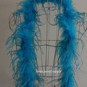 Op de afbeelding: Een lange, fel turquoise verenboa gedrapeerd over een wit draadmannequin. De boa is gemaakt van zachte, pluche veren en is perfect om een vleugje glamour toe te voegen aan elk feest of evenement.