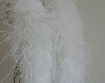 Puede incluir: Un boa de plumas de avestruz blanco drapeado sobre un maniquí. El boa es suave y esponjoso, y sería perfecto para un disfraz o una fiesta.