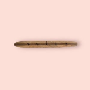 May include: A wooden coat rack with a natural finish and five metal hooks. The rack is shaped like a long oval.