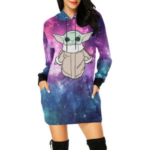 Puede incluir: Vestido con capucha con un dise&ntilde;o de galaxia en morado, azul y turquesa. El vestido presenta un gr&aacute;fico de un personaje de dibujos animados. Tiene mangas largas con pu&ntilde;os negros y dos bolsillos delanteros.