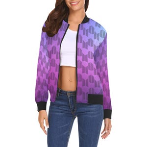 Peut inclure: Veste de bombardier violette et bleue avec un motif géométrique répétitif. La veste a un col, des poignets et un ourlet noirs. La veste est zippée et possède des poches.