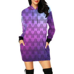 Könnte beinhalten: Ein lila Kapuzenkleid mit geometrischem Muster und Farbverlauf. Die langen Ärmel haben schwarze Bündchen und das Kleid hat Taschen. Dieses Freizeitkleid ist ein modernes Design.
