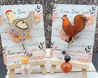 May include: Two glitter chicken themed retractable badge reels with orange and clear beads. The cards say "Nana Bear Love I am a ..." and "Thank you Nanabearlove Etsy.com".