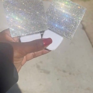 Puede incluir: Dos luces nocturnas blancas con un diseño cuadrado en forma de diamante. Las luces están enchufadas a una toma de corriente.