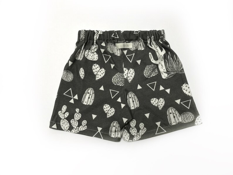 May include: Black shorts with a white cactus print. The shorts have an elastic waistband and a drawstring.