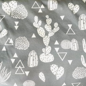 May include: A gray fabric with a white repeating pattern of cacti, succulents, and geometric shapes. The fabric has a soft, textured feel.