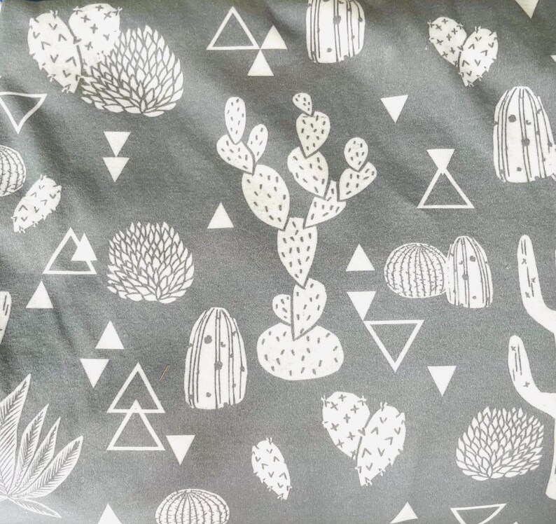 May include: A gray fabric with a white repeating pattern of cacti, succulents, and geometric shapes. The fabric has a soft, textured feel.