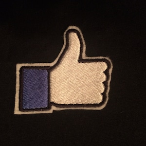 May include: A blue and white embroidered thumbs up icon. The icon is a popular symbol of approval and positivity.