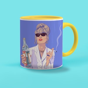 Könnte beinhalten: Eine gelbe und blaue Keramiktasse mit einem Cartoon-Bild einer Frau mit blonden Haaren, die eine Sonnenbrille und einen weißen Blazer trägt. Sie hält eine Flasche Wodka und eine Zigarette in der Hand. Die Tasse hat einen gelben Henkel.