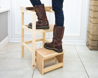 May include: A wooden step stool with two steps. The top step is made of plywood and the bottom step is made of solid wood. The stool is painted a natural wood color.