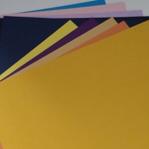 May include: A stack of colorful cardstock paper in various shades of blue, purple, yellow, orange, pink, and beige.