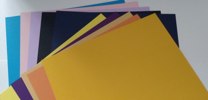 May include: A stack of colorful cardstock paper in various shades of blue, purple, yellow, orange, pink, and beige.