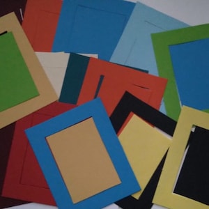 May include: Assortment of colourful paper picture frames in various sizes. The frames are made of cardstock and have a cut-out design for inserting photos.