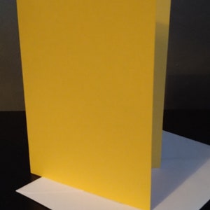 Peut inclure: Une carte jaune vierge avec une enveloppe blanche. La carte est debout sur l'enveloppe.