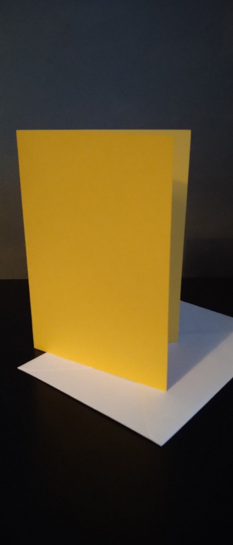 Peut inclure: Une carte jaune vierge avec une enveloppe blanche. La carte est debout sur l'enveloppe.