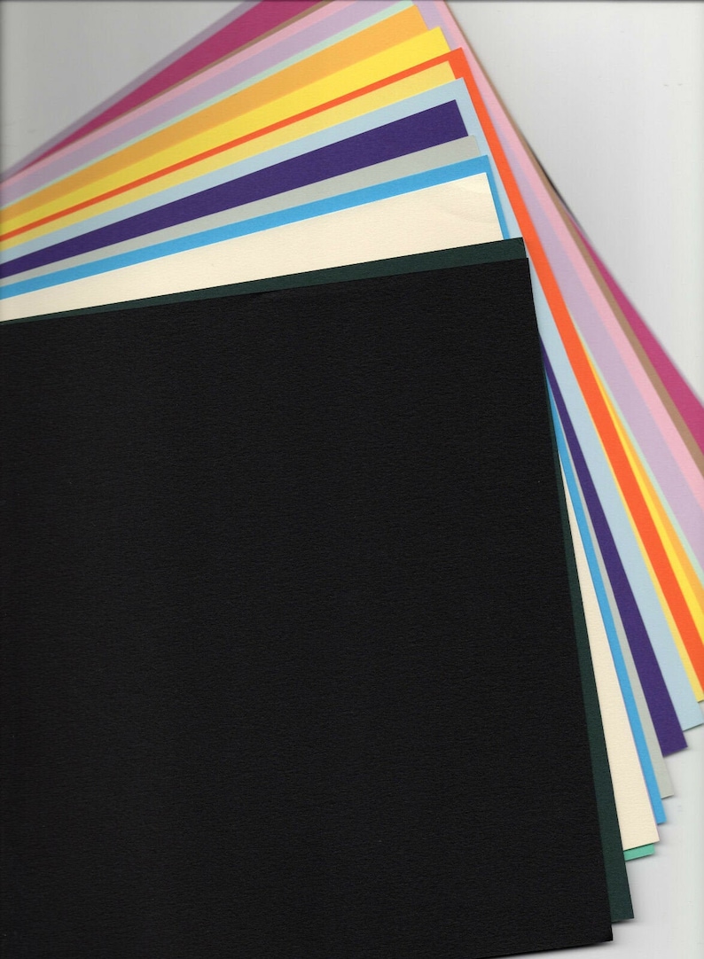 May include: A stack of colorful cardstock paper in various shades of pink, purple, blue, green, yellow, and orange. The top sheet is black.