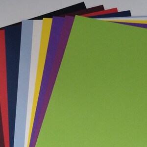 May include: A stack of 12 different colored cardstock paper sheets. The top sheet is a bright green color.