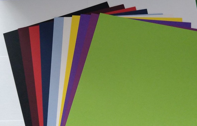 May include: A stack of 12 different colored cardstock paper sheets. The top sheet is a bright green color.